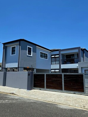 A modern two-story building with a garage, a balcony, and a clear blue sky. - El Pantheon Guest House and Apartments (Cape Town)