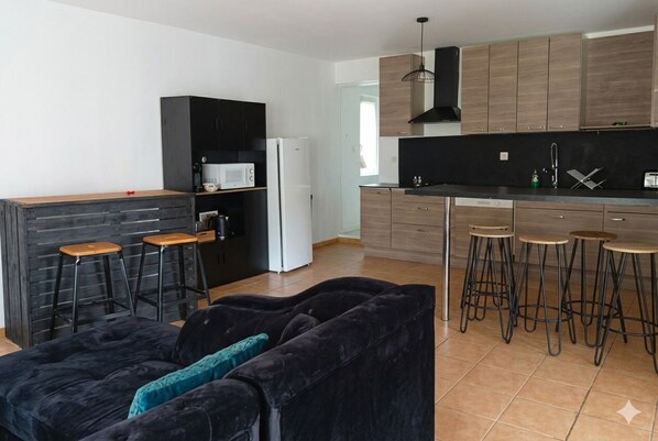 Une cuisine moderne avec des meubles en bois, un plan de travail noir et des tabourets de bar.