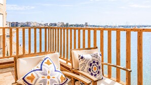 A balcony with wooden railings, two cushioned chairs, and a view of a marina and cityscape. - 2 bedroom beach front apartment in Torrevieja (Torrevieja)