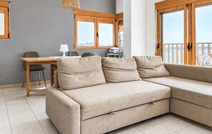 Ein modernes Wohnzimmer mit einer Couch, einem Esstisch und einem Sessel.