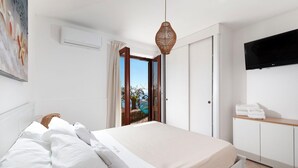 Ein Schlafzimmer mit Bett, Fernseher, Kleiderschrank und Blick ins Freie.