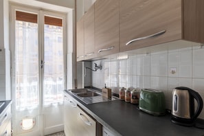 A kitchen with wooden cabinets, a sink, a toaster, and a kettle. - GuestHost - Bright Balcony Apartment Eppan (Rome)
