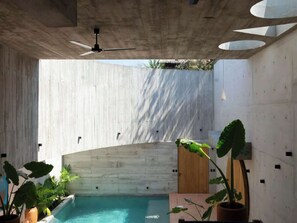 Ein moderner Poolbereich im Innenbereich mit Betondecke, Holzvertäfelung und Deckenventilator.