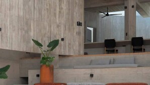 Un área de estar moderna al aire libre con un sofá, sillas y una planta en maceta.