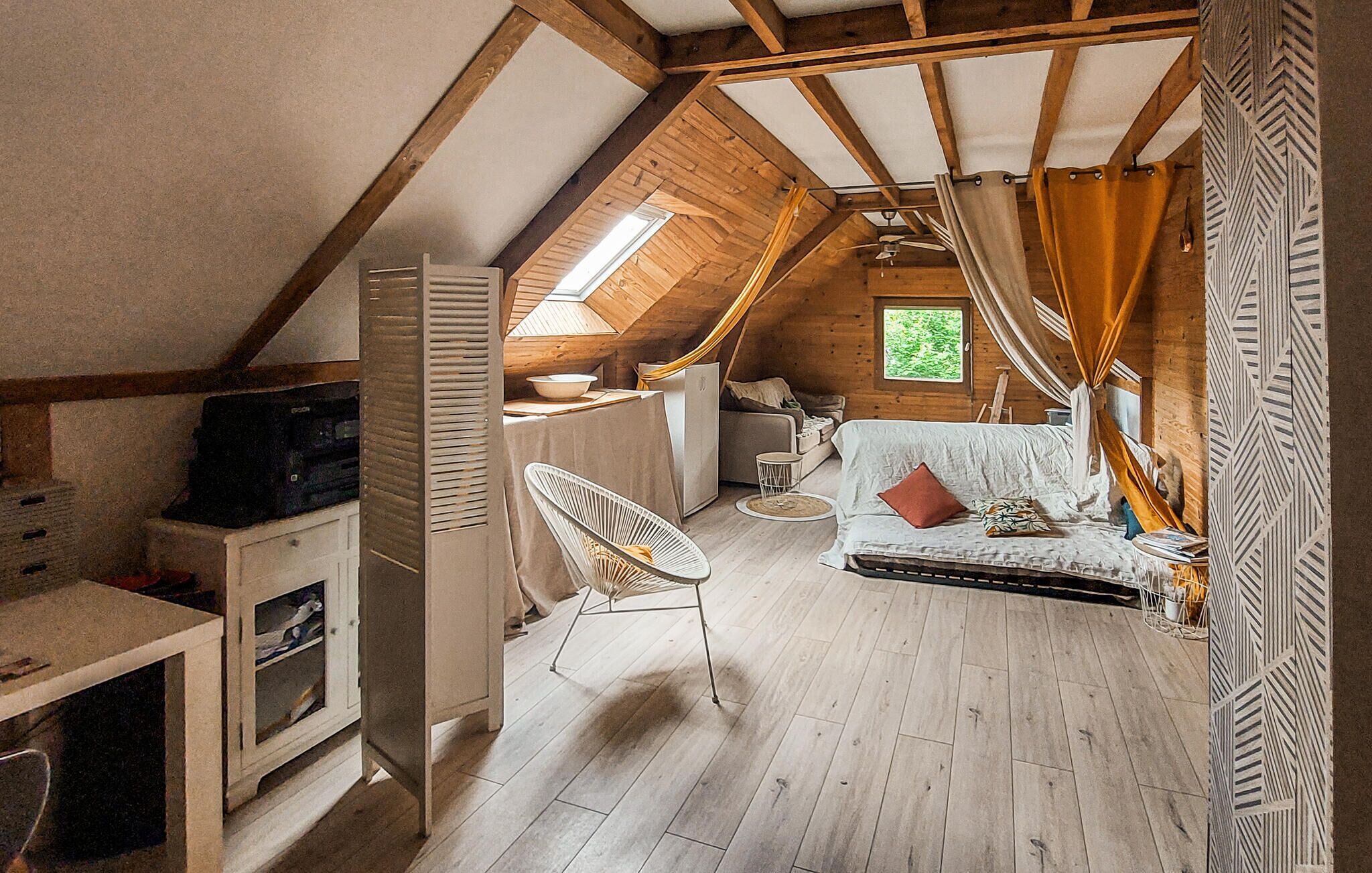 A cozy attic bedroom with a sloped ceiling, a bed, a small table, and a chair.