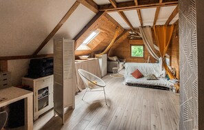 Ein gemütliches Schlafzimmer im Dachgeschoss mit schrägen Wänden, einem Bett, einem kleinen Tisch und einem Stuhl.