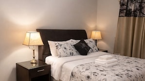 A neatly made bed with a floral bedspread, two bedside lamps, a dark headboard, and a small bedside table with a lamp. - Private Room Near SQ 1 • Self Check-in • 2 min to Transit (Mississauga)