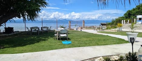 A patio with outdoor furniture, a concrete pathway, and a view of the ocean.