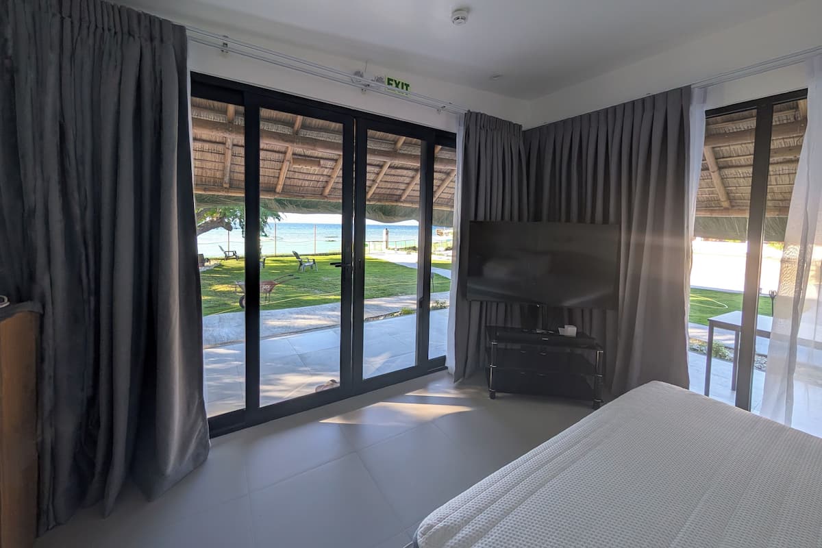 A room with a bed, a TV, and a view of the beach.