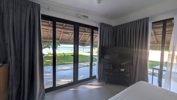 A room with a bed, a TV, and a view of the beach.