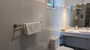 Un baño moderno con inodoro, lavamanos y espejo.