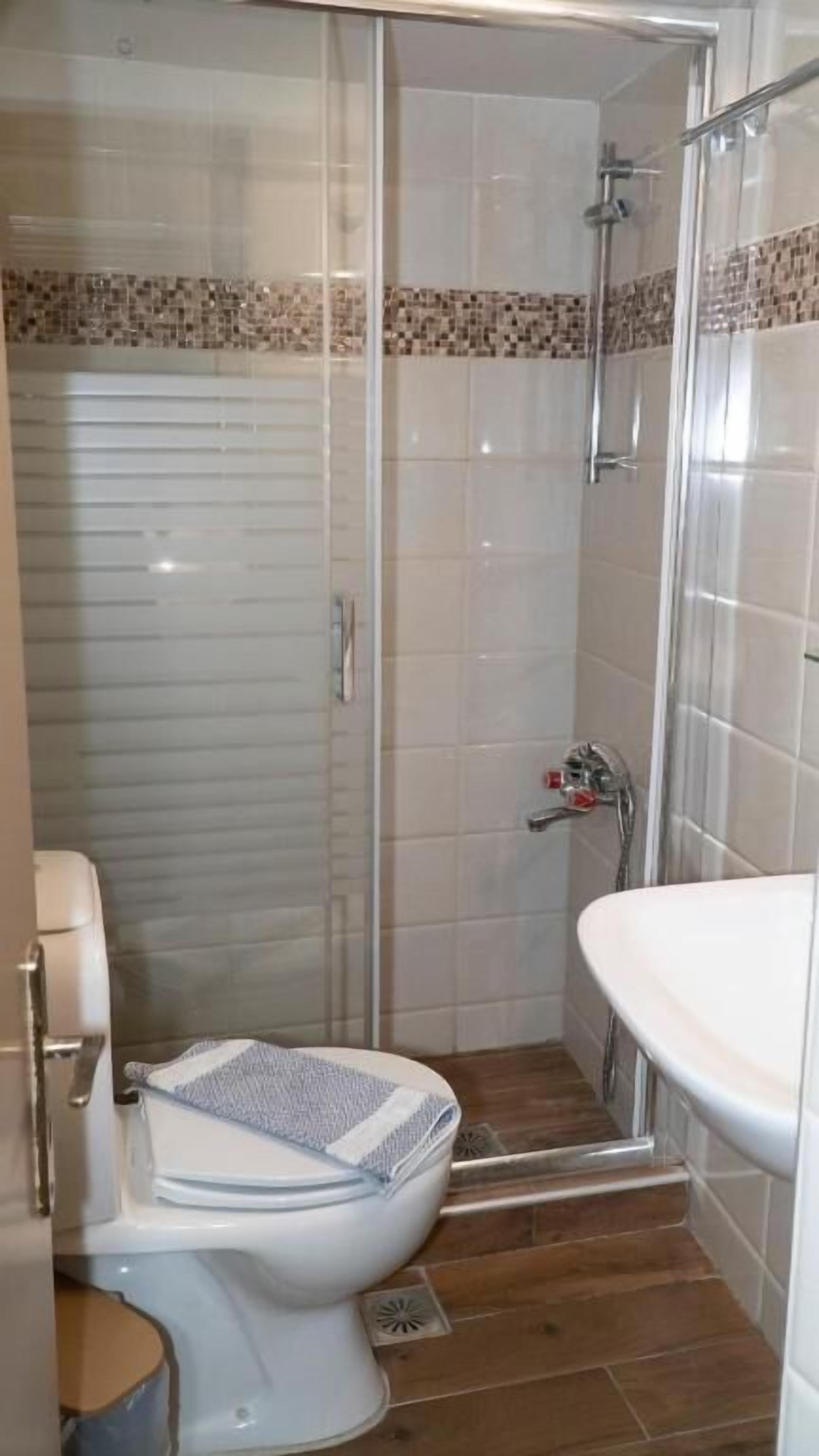 A bathroom with a toilet, shower, and sink.