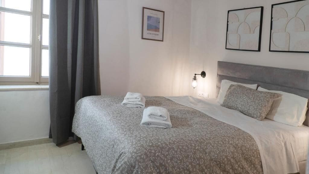 A neatly made bed with folded towels, a headboard, and wall art.