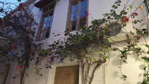 Ein Gebäude mit weißer Fassade, einer braunen Tür und einem Fenster mit einem Metallgitter.