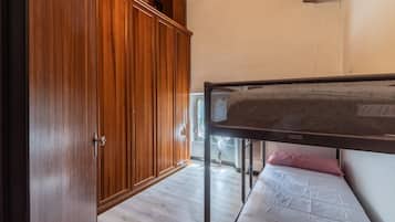 Une chambre avec une armoire en bois, un lit superposé et une fenêtre.