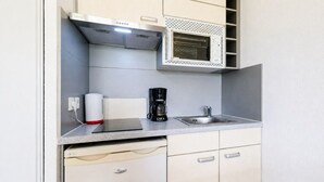 Une petite cuisine équipée d’un four à micro-ondes encastré, d’une machine à café et d’un évier.