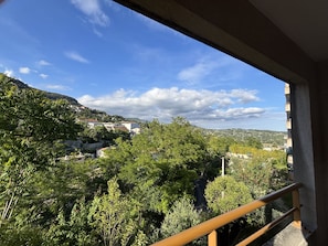A balcony with a view of a hillside town, trees, and a clear sky. - A relaxing break in Grasse | Swimming pool, balcony & nature (Grasse)