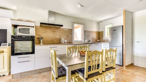 A kitchen with a dining table, chairs, and a refrigerator. - Beautiful Villa - Sleeps 6 - Family-friendly (Homps)