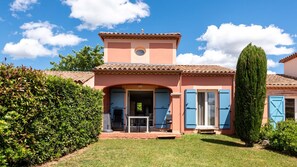A two-story house with a tiled roof, a small tower-like structure on the roof, and a front door with blue shutters. - Beautiful Villa - Sleeps 6 - Family-friendly (Homps)