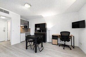Ein kompakter Wohnraum mit Küchenzeile, Essbereich und Arbeitsplatz.