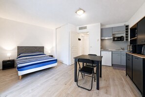 Ein modernes Hotelzimmer mit Bett, Schreibtisch, Stuhl, einer Küchenzeile und einem Badezimmer.