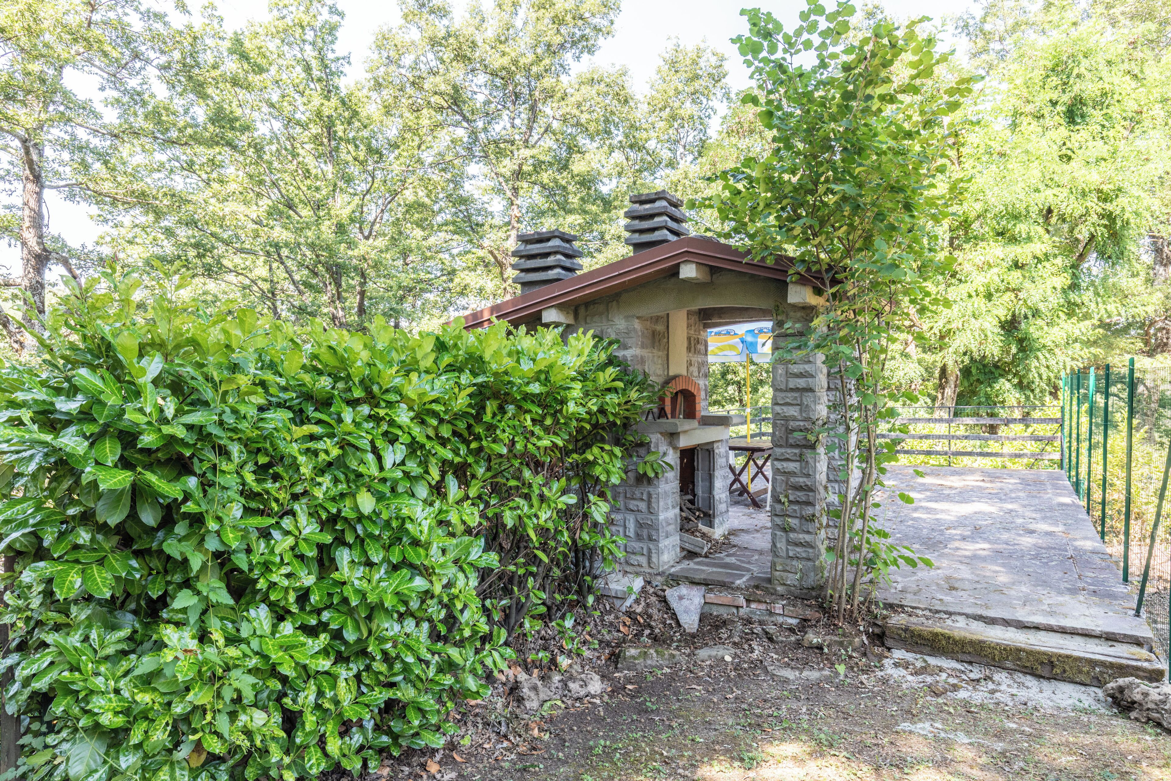 A stone structure with a roof, surrounded by dense green foliage.