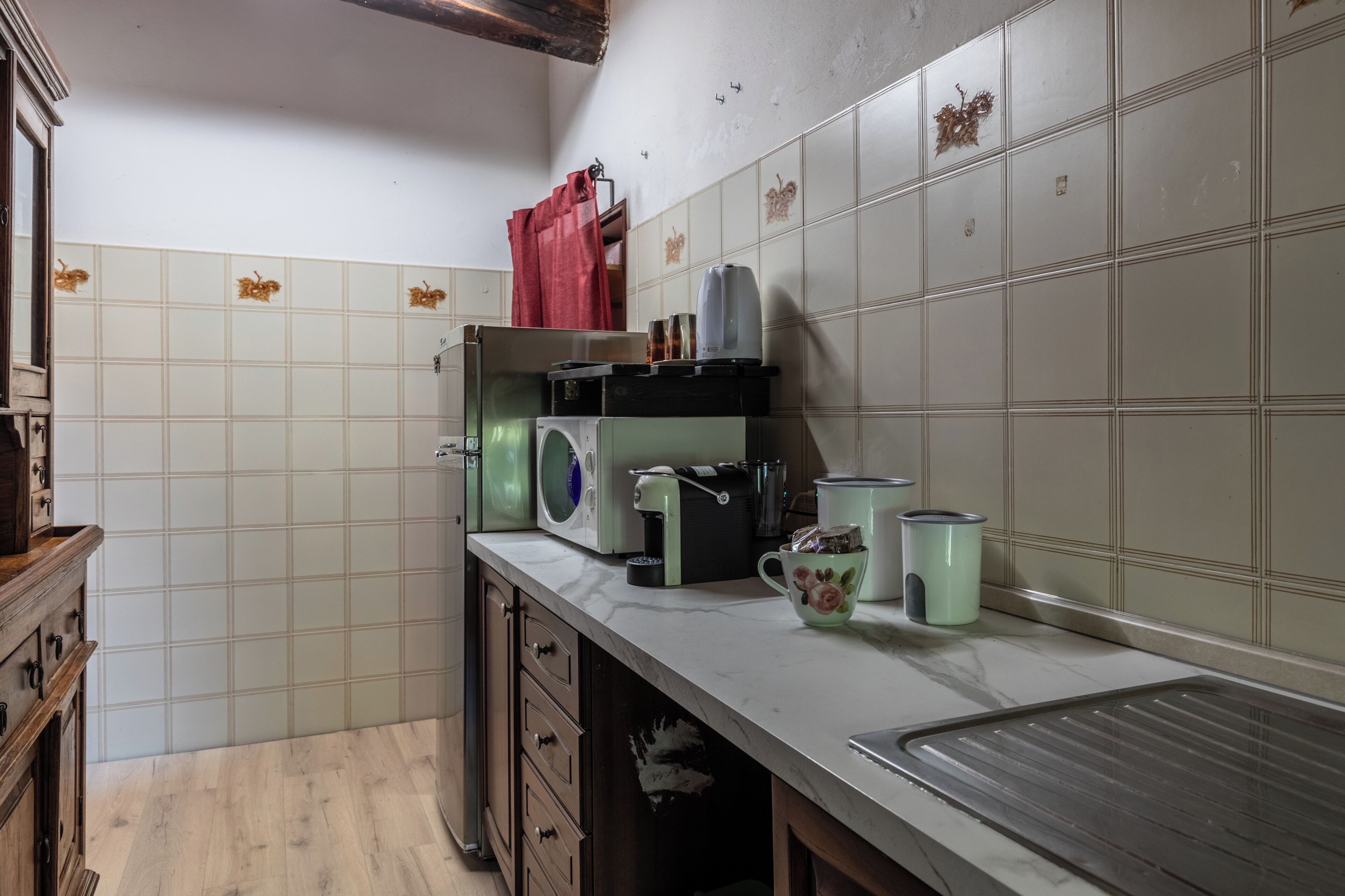 A kitchen with a sink, a microwave, a coffee maker, and a red bag on the counter.
