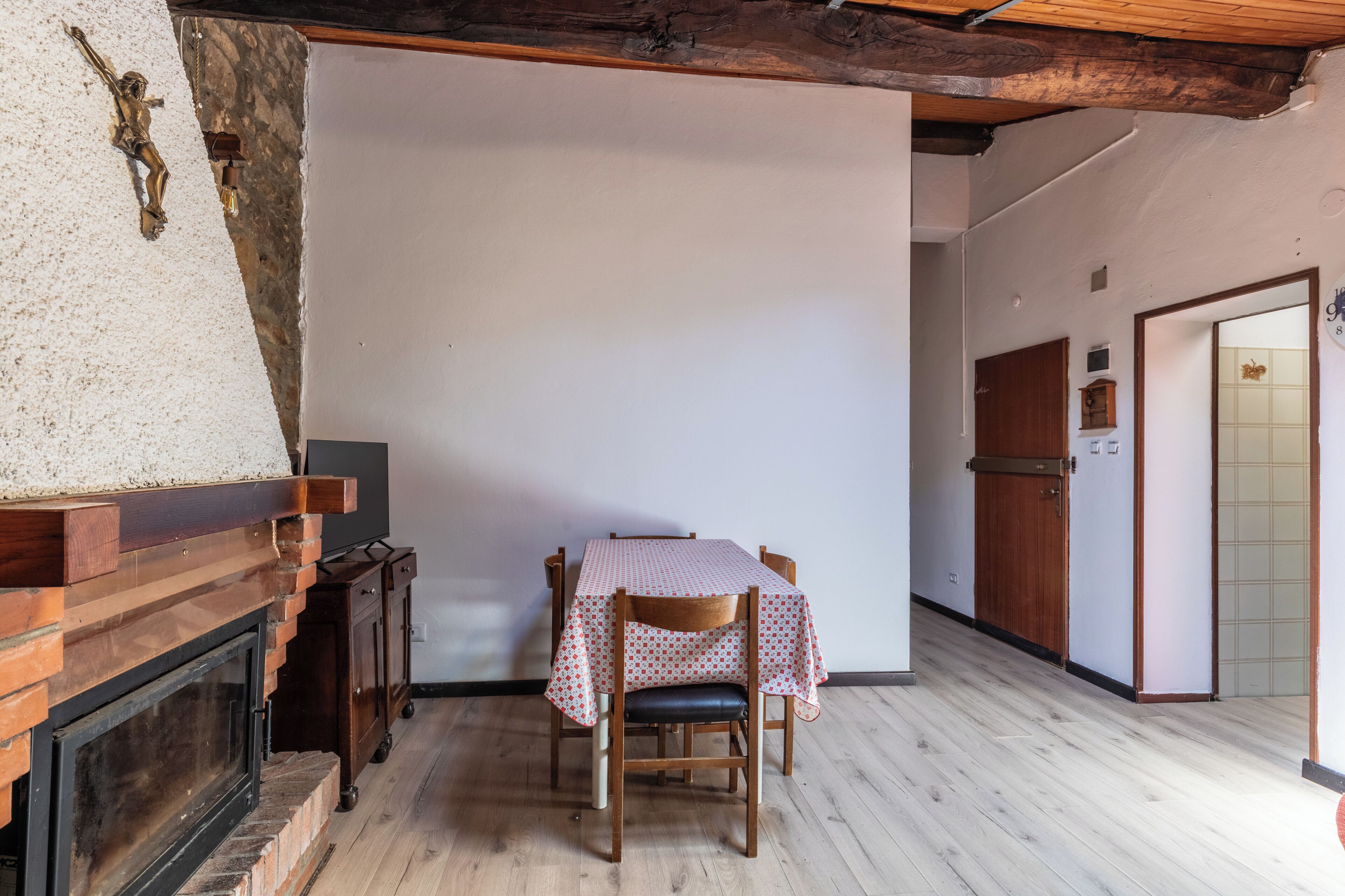 Un espace repas comprenant une table, des chaises, une cheminée et un couloir menant à une porte.