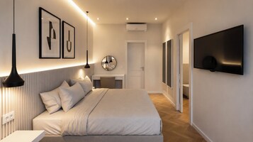 Una camera da letto moderna con un letto, lampade da comodino, una TV a schermo piatto e opere d'arte incorniciate al muro.