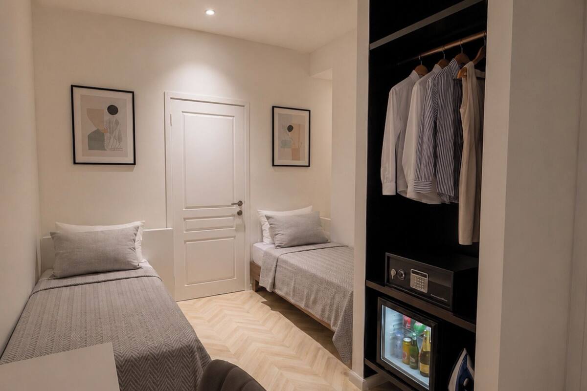 Un dormitorio con dos camas, un armario y un minibar.
