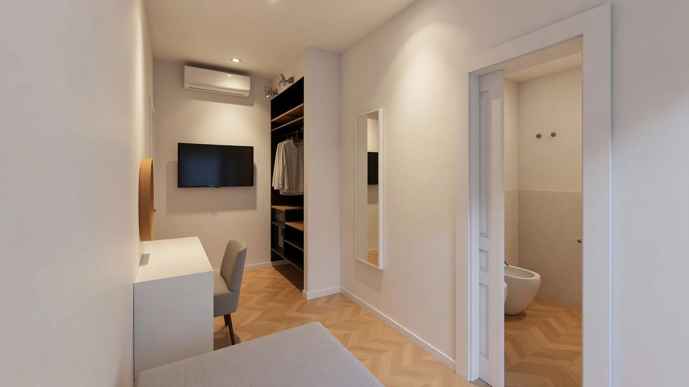 Un pasillo moderno y bien iluminado con un escritorio, una silla y un televisor empotrado. Se observa un armario con ropa colgada y un inodoro blanco.