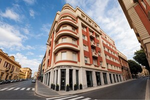 Un edificio a più piani con una facciata curva, un ingresso imponente e un cielo sereno.