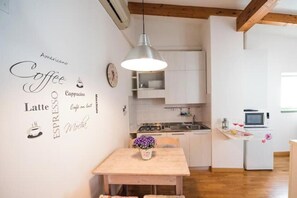 Eine moderne Küche mit weißen Schränken, einem Holzespeisetisch und einer Pendelleuchte.