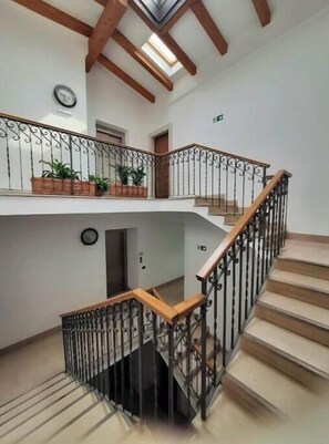 Ein mehrgeschossiges Interieur mit Treppe, Holzbalken und Topfpflanzen.