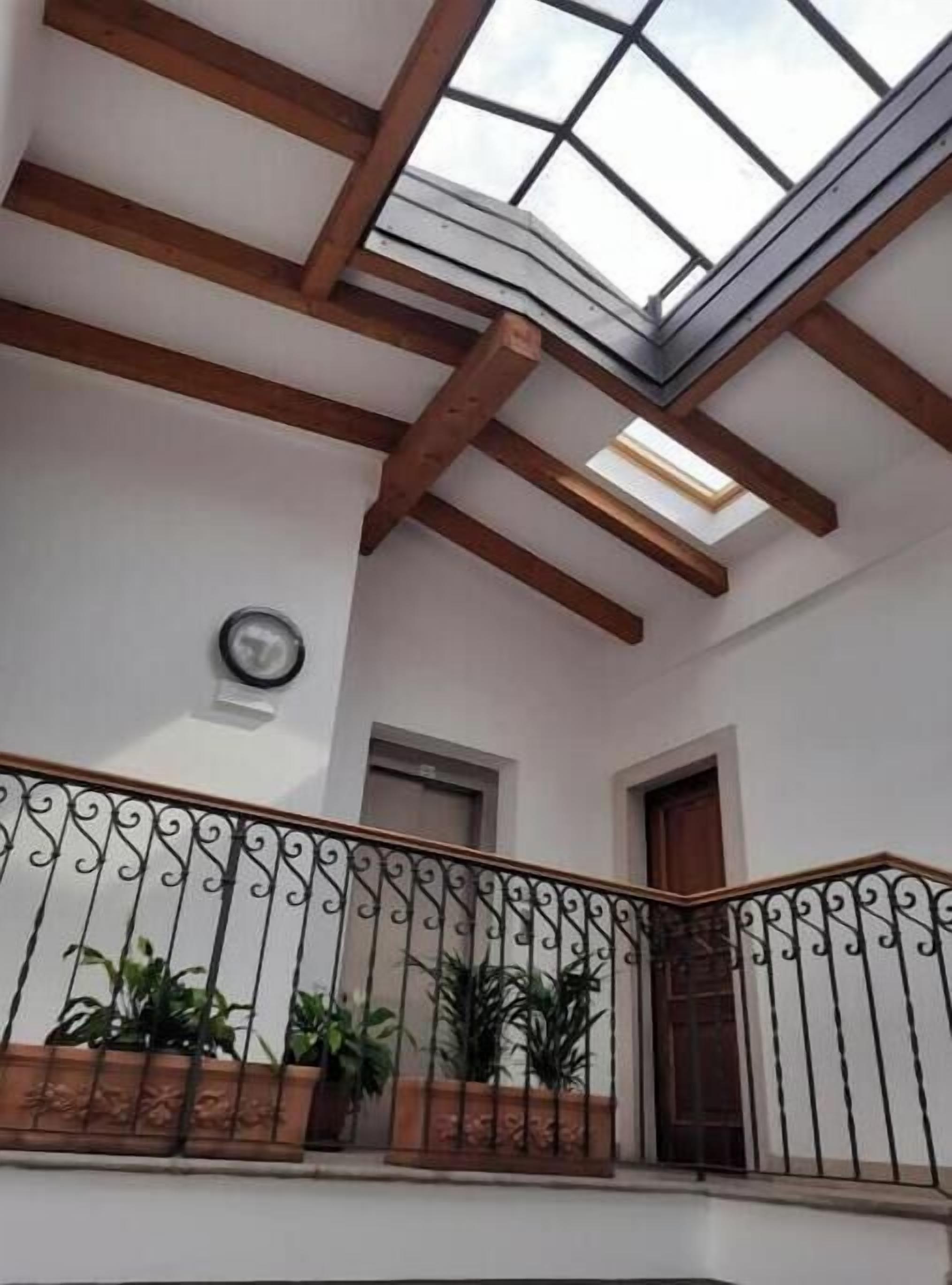 A balcony with a wrought iron railing, potted plants, and a skylight.