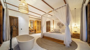 Ein Schlafzimmer mit einem Himmelbett, einer Badewanne und einem Holzschrank.