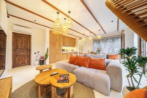 Un salon moderne avec un canapé, une table basse en bois et des lampes suspendues en osier.