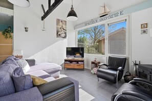 Ein modernes Wohnzimmer mit einer Couch, einem schwarzen Ledersessel, einem Fernseher und einem Kamin.