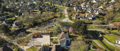 Vista aérea de una zona residencial con casas, un río y una playa al fondo.