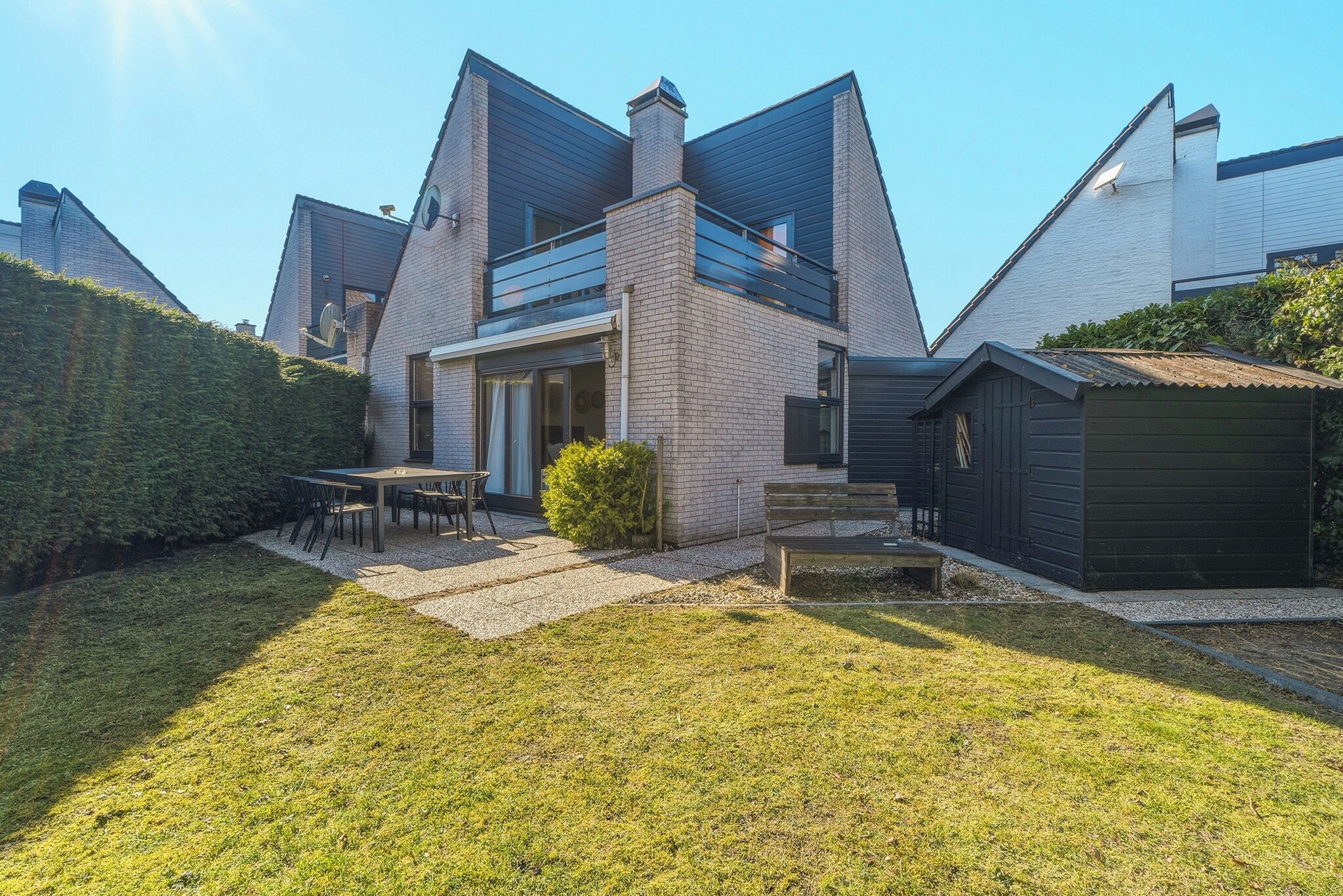 A modern house with a brick exterior, a covered patio, and a small garden.