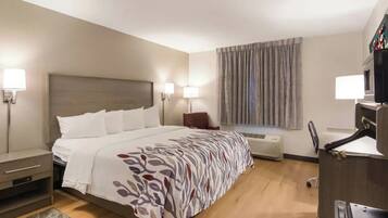 A hotel room with a bed, bedside tables, a desk, and a window with curtains.