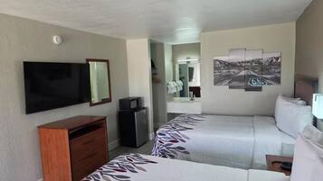 A hotel room with two beds, a television, a desk, and a mirror.
