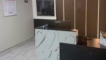 A reception desk with a marble design, a computer monitor, and a framed picture on the wall.