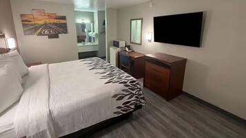 A hotel room with a bed, a desk, a TV, and a mirror.