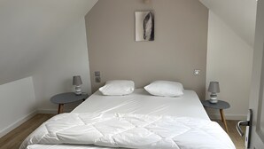 A bedroom with a bed, two bedside tables, a wall-mounted lamp, and a painting. - Holiday Home 'Gite Baie' with Private Terrace, Private Garden and Wi-Fi (Telgruc-sur-Mer)