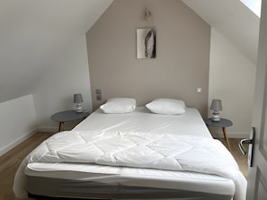 Ein Schlafzimmer mit einem Bett, zwei Nachttischen, einer Wandlampe und einem Bild.