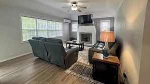 A living room with a sofa, a coffee table, a fireplace, and a ceiling fan. - Peaceful Bermuda Retreat Near Beaches & Royal Naval Dockyard (Sandys Parish)