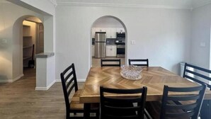 A dining area with a wooden table and chairs, an arched doorway leading to a kitchen, and a ceiling fan. - Peaceful Bermuda Retreat Near Beaches & Royal Naval Dockyard (Sandys Parish)