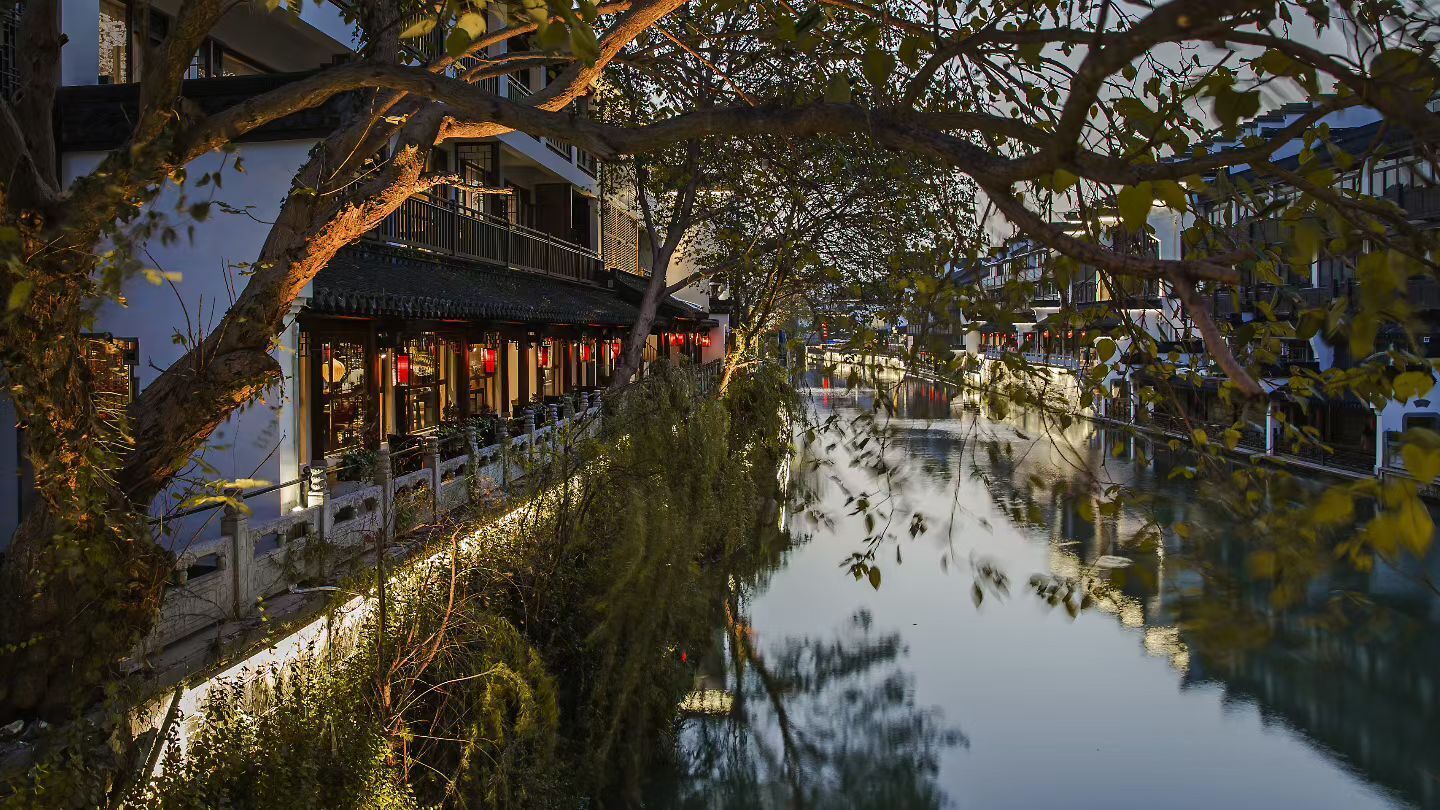 Un bâtiment traditionnel qui se reflète dans l’eau, avec un pont et des arbres.