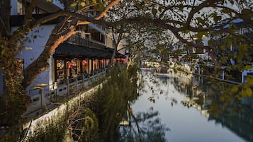 Un bâtiment traditionnel qui se reflète dans l’eau, avec un pont et des arbres.